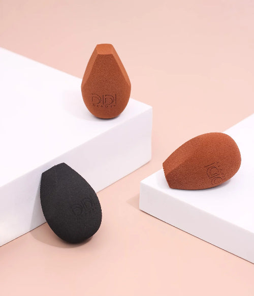 Three makeup sponges on a light pink and white background