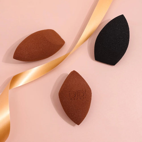 Three makeup sponges on a pink background with a gold ribbon